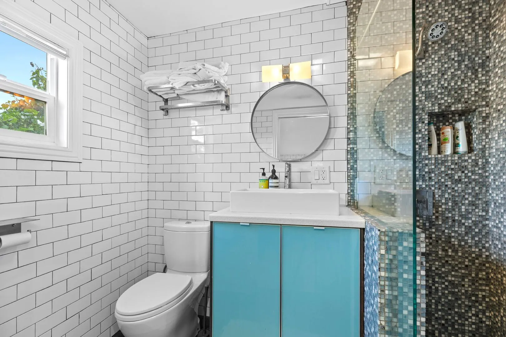ADU bathroom with white subway tile, glass shower and teal vanity
